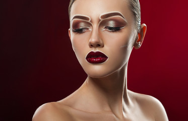 Creative chic. Beautiful young dark haired model wearing artistic concept makeup on red background