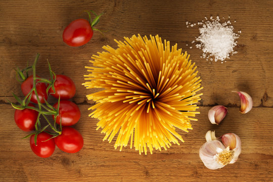 ingredienti pasta, pomodoro, aglio, sale su legno