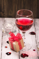 Valentines day card with glass of rose wine, gift box, hearts and candle. Selective focus