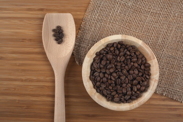 Coffee beans in bowl on wooden background