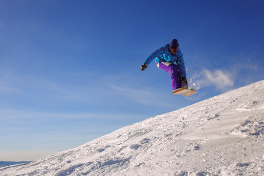 Snowboarder jumping through air with deep blue sky in background