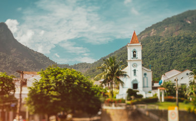 Fototapeta na wymiar Church with bell tower in the village, wooded mountains in the background, Brazil, tilt shift shooting