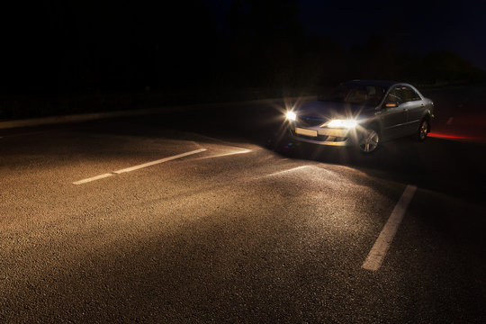 At night, light car with lights on, on the road