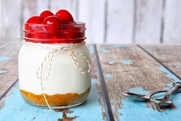 Meubelstickers Sweet cherry cheesecake in a mason jar on a rustic wood background © Jenifoto