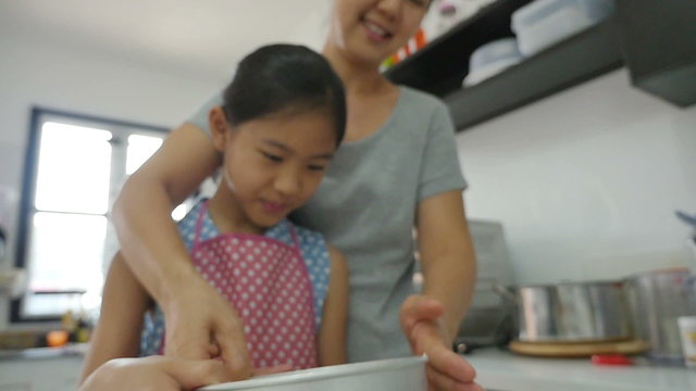 Happy Asian mother baking cookie with little daughter in apron, Tilt down shot