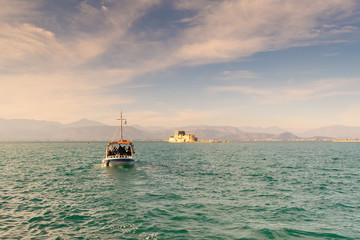 Obraz premium Boat with local people and tourists going to Bourtzi castle for a tour at Nafplio in Greece. 