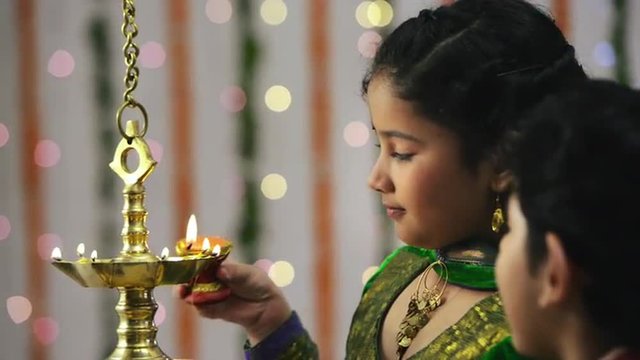 Locked-on shot of two children lighting an oil lamp during Diwali festival