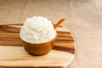 Shea butter in the wooden bowl stands on the wooden board, on th