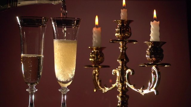 Champagne. Two flutes with champagne by candlelight in a golden candelabrum. 