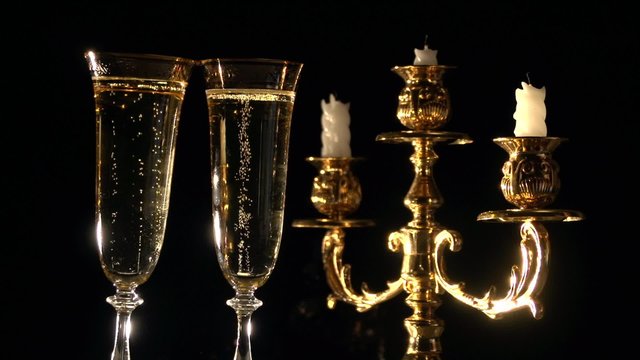 Champagne. Two flutes with champagne by candlelight in a golden candelabrum. 