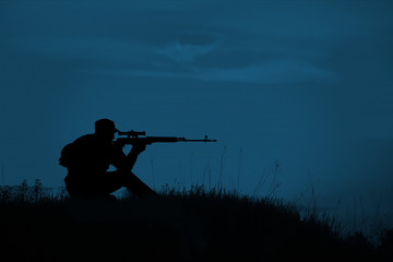 Silhouette of military sniper with sniper rifle at night. shot, - obrazy, fototapety, plakaty
