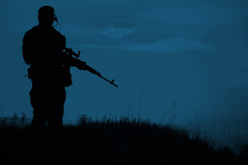 Silhouette of military sniper with sniper rifle at night. shot