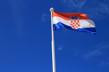 Flag of Croatia with flag pole waving in the wind with blue sky in background