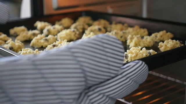 Baker putting cookies into the oven, Slow motion shot