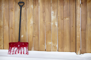 snow shovel leaning agains a fence