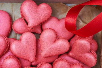 Obraz premium Heart-shaped macarons with flowers and ribbon on a wooden table. Creative decoration for Valentine's Day