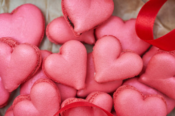 Obraz premium Heart-shaped macarons with flowers and ribbon on a wooden table. Creative decoration for Valentine's Day