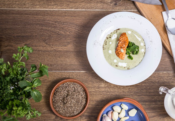 Cream of broccoli soup with salmon top view a wooden background