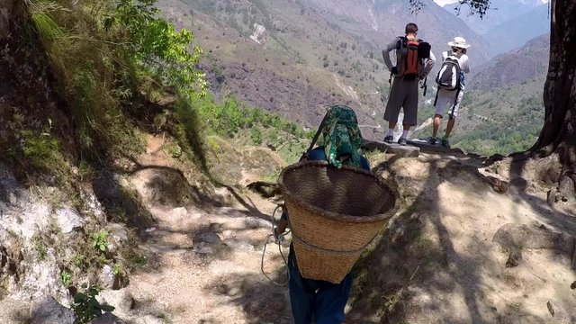 Tourists enjoy beautiful Himalaya mountain view and local girl walks down the hill with a basket