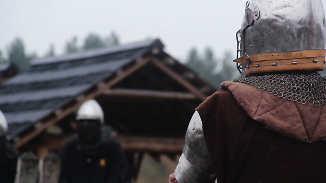 Brave warrior in steel armor waiting for enemy's attack on rainy battle field