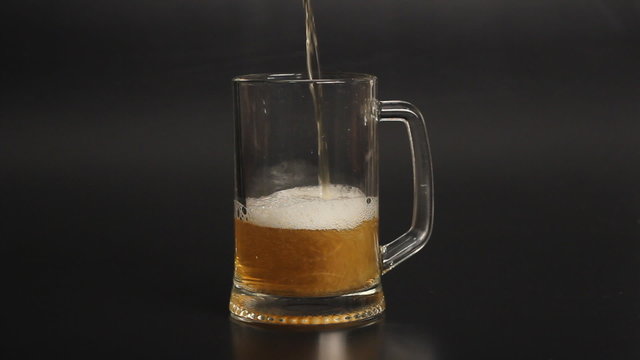 light wheat beer glass is poured into a glass on a black background 