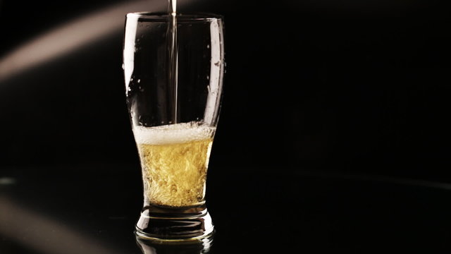 light wheat beer glass is poured into a glass on a black background 