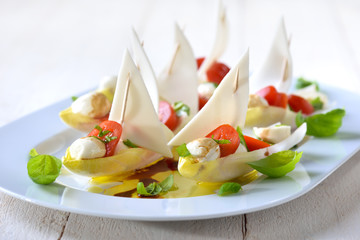 Chicoree-Schiffchen mit Caprese-Füllung: Minitomaten und Mozzarella-Bällchen; Chicory leaves stuffed with cherry tomatoes and mozzarella balls