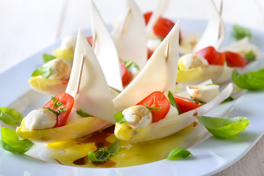 Chicoree-Schiffchen mit Caprese-F&uuml;llung: Minitomaten und Mozzarella-B&auml;llchen; Chicory leaves stuffed with cherry tomatoes and mozzarella balls