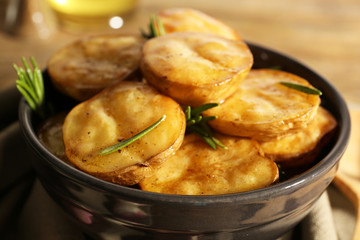 Delicious baked potato with rosemary in bowl on table close up