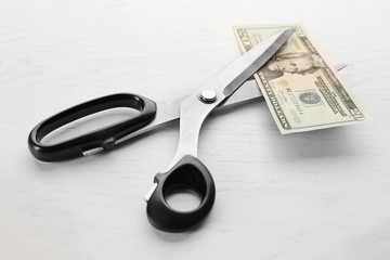Scissors cuts dollar banknote on table