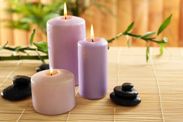 Fototapeta na wymiar Purple candles with spa stones and bamboo on table