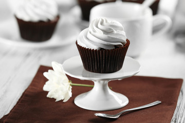 Delicious chocolate cupcake with cream on served table, close up