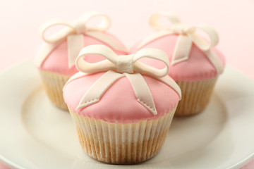 Tasty cupcakes with bow on color wooden background