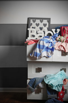 Child clothes in wooden chest of drawer, close up