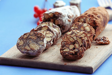 Chocolate salami on a chopping board over blue background, close up