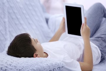 Boy using tablet on a sofa at home