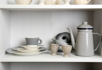 Fototapeta na wymiar Tableware on shelves in the kitchen cupboard