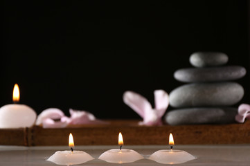 Fototapeta na wymiar Spa still life with candles in water on dark background