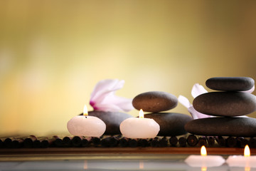 Spa still life with stones, candles and flowers in water on blurred background
