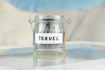 Glass jar with dollar banknotes for travel on a table