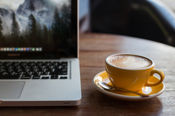 Hot art Latte Coffee in a cup and laptop on wooden table
