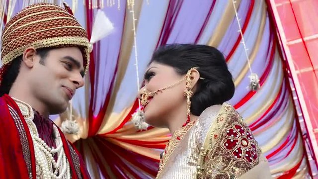 Pan shot of Indian bride and groom in traditional wedding dress talking to each other