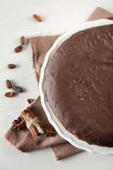 Tasty chocolate frosting cake on light table, close up
