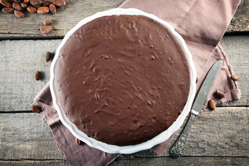 Tasty chocolate frosting cake on wooden table