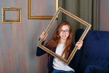 Teen girl with glasses holding an empty picture frame.