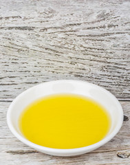 Olive oil in white bowl over wooden background