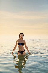 Fototapeta na wymiar Healthy Lifestyle. Woman Standing In Sea At Sunset. Summer Vacat
