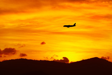 Obraz premium Beautiful Landscape. Travel On Summer Vacations To Thailand, Asia. Silhouette Of Flying Aircraft ( Airplane ) In Beautiful Orange Sky, Hills Of Tropical Island During Sunset. Tourism. Transportation.
