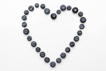 Blueberries hollow heart in a centre on white background directly from above