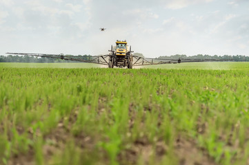 Farm tractor sprays a field toxins from pests, unmanned helicopter takes off process